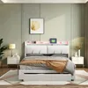 A bedroom scene featuring a white upholstered bed with a built-in headboard shelf that has LED lighting. Produktbild-Vorschau