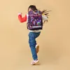 A young girl is jumping with a backpack on her back. Produktbild-Vorschau