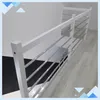 A white wooden handrail with silver metal bars is shown in a room with a black and white patterned floor and light wood flooring. Náhled obrázku produktu