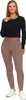 A woman wearing black long-sleeved top and brown leggings with white sneakers. Produktbild-Vorschau