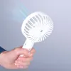 A hand holding a white portable fan that is emitting blue wisps of air. Produktbild-Vorschau