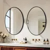 A modern bathroom vanity with two oval mirrors, sinks, faucets, and toiletries. Podgląd zdjęcia produktu