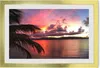 A framed picture of a sunset over the ocean with a palm tree in the foreground. Produktbild-Vorschau
