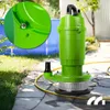 A green submersible pump is placed on a paved patio next to a grassy area and a blue pool. Podgląd zdjęcia produktu