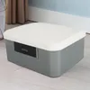 A gray and white lockable storage box with a combination lock is shown on a wooden floor. Produktbild-Vorschau