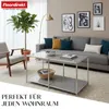 A living room scene featuring a sofa, coffee table, armchair, and plant, with artwork on the wall. Anteprima dell’immagine prodotto