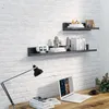 A desk with a laptop and a lamp against a white brick wall with shelves above. Náhľad obrázku produktu