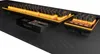 A close-up, angled view of a black keyboard with orange backlighting, placed on a black textured surface. Produktbild-Vorschau