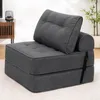 A dark gray foldable sofa bed with cushions is shown in a room. Náhled obrázku produktu