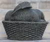A close-up of a dog urn in the shape of an angel figure, resting in a woven basket. Anteprima dell’immagine prodotto