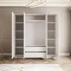 An open white wardrobe with shelves and drawers, set against a neutral background. Produktbild-Vorschau
