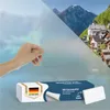 A hand is holding a frosted window film, with a scenic village and mountains in the background. A product box is in the foreground. Náhľad obrázku produktu