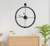 A black metal wall clock is mounted on a white wall above a wooden cabinet. Podgląd zdjęcia produktu