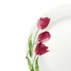 A close-up view of a white plate with a floral design of pink tulips and green leaves. Náhľad obrázku produktu