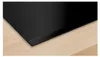 A close-up view of a black induction hob integrated into a light wood countertop. Produktbild-Vorschau