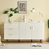 A white sideboard with gold accents, a plant, a lamp, and artwork on a light yellow wall. Produktbild-Vorschau