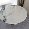 A round dining table with a marble-like ceramic top and a metallic base, shown in a room setting. Produktbild-Vorschau
