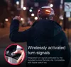 A person wearing a black helmet with integrated lights is cycling at night, with a close-up inset showing a hand operating a remote control. Anteprima dell’immagine prodotto