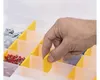 A hand is shown adjusting a divider in a clear plastic organizer box filled with various small hardware items. Voir les images du produit