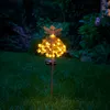 A solar-powered garden stake with a fairy design and LED lights illuminates a lawn at dusk. Produktbild-Vorschau