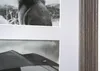 A close-up view of a matted picture frame with two black and white photographs. The top photo shows the back of a monkey, and the bottom photo shows an umbrella in the rain. The frame itself has a wood-grain texture. Náhled obrázku produktu