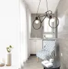 A balcony or small room with a chair, a small table, and a unique bicycle-shaped pendant light. Podgląd zdjęcia produktu