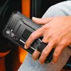 A person's hand holding a black smartphone case with a built-in stand. Produktbild-Vorschau
