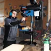 A man is using a drill press in a workshop. Produktbild-Vorschau