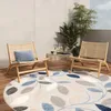 An outdoor patio scene with two chairs, a coffee table, plants, and a circular rug. Náhľad obrázku produktu
