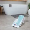 A baby bath lounger is placed on the floor in front of a bathtub. Náhľad obrázku produktu