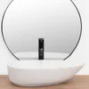 A white countertop basin with a black faucet in front of a large circular mirror. Náhled obrázku produktu