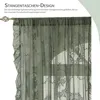 A close-up view of a green lace curtain with a floral pattern, hanging from a curtain rod. Produktbild-Vorschau