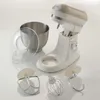 A kitchen mixer with its accessories laid out on a white surface. Náhled obrázku produktu