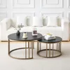Two round coffee tables with black marble-effect tops and gold metal frames are placed on a light carpet in front of a white sofa with white cushions. Voir les images du produit