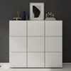 A white shoe cabinet with decorative items on top, set against a dark gray wall. Produktbild-Vorschau