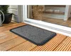 A doormat is placed on a wooden deck in front of a glass door. Podgląd zdjęcia produktu
