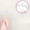 A close-up view of a white metal coat rack with a pink garment hanging on it. A purple circle highlights a hook detail. Náhled obrázku produktu