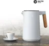 A white electric kettle with a wooden handle and a white coffee cup with a saucer are placed on a marble countertop. Produktbild-Vorschau