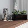 A black rectangular ceramic planter with green plants and a lighthouse decoration sits on a wooden surface next to a gray anchor decoration and a starfish. Náhled obrázku produktu