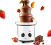 A chocolate fountain with various fruits and a slice of cake, set against a white background. Podgląd zdjęcia produktu