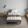 A bedroom scene with a single bed, nightstand, and lamp. Voir les images du produit