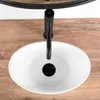 A top-down view of a white oval sink with a black faucet on a wooden countertop. Náhled obrázku produktu