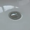 A close-up view of a drain in a white bathtub. Produktbild-Vorschau