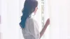 A woman stands by a window, holding back a sheer white curtain. The lighting is soft and diffused. Produktbild-Vorschau