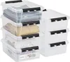 A stack of clear plastic storage bins with black latches, some filled with folded clothes and a puzzle box. Anteprima dell’immagine prodotto