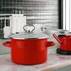 A red pot with a glass lid sits on a kitchen counter, with other kitchen items in the background. Produktbild-Vorschau