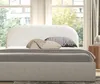A bedroom scene with a bed in the foreground and a window with trees in the background. Anteprima dell’immagine prodotto