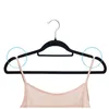 A black velvet hanger with a pink camisole strap draped over it, against a white background. Produktbild-Vorschau