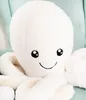 A close-up of a white plush octopus toy sitting on a light blue chair. Produktbild-Vorschau