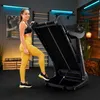 A woman is posing next to a treadmill in a home gym setting. Produktbild-Vorschau